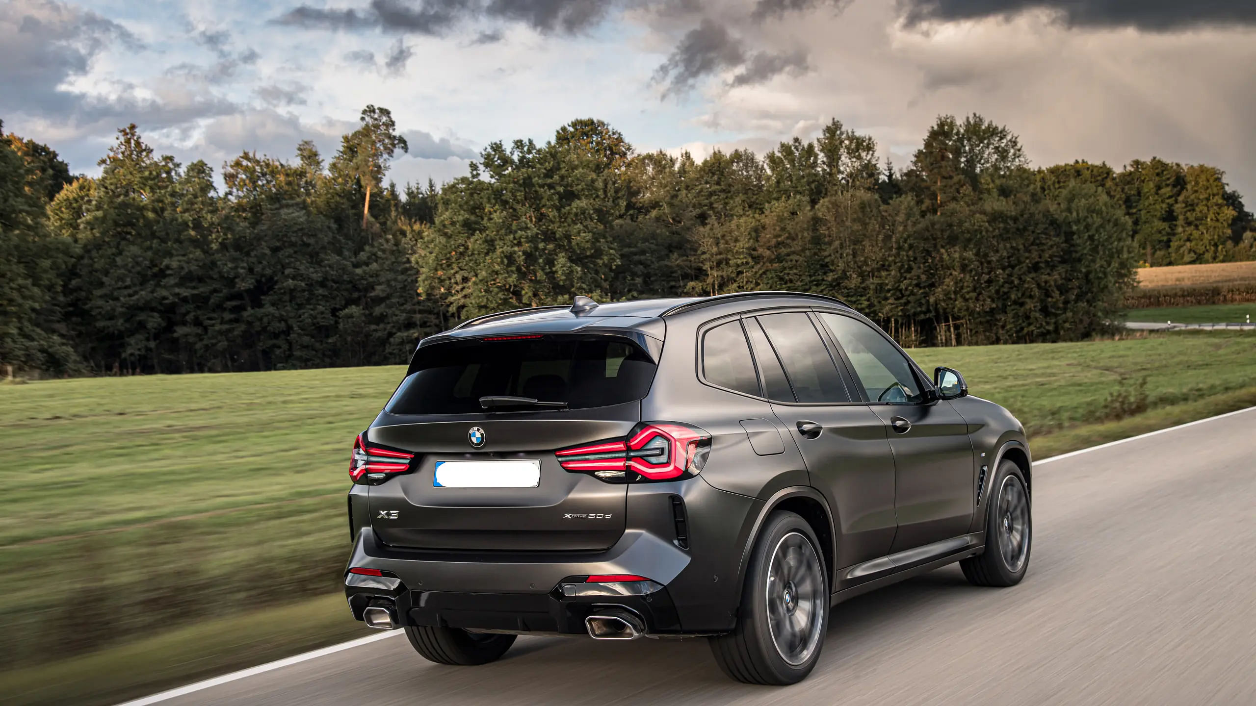 2024 BMW X3 rear view while driving down a road