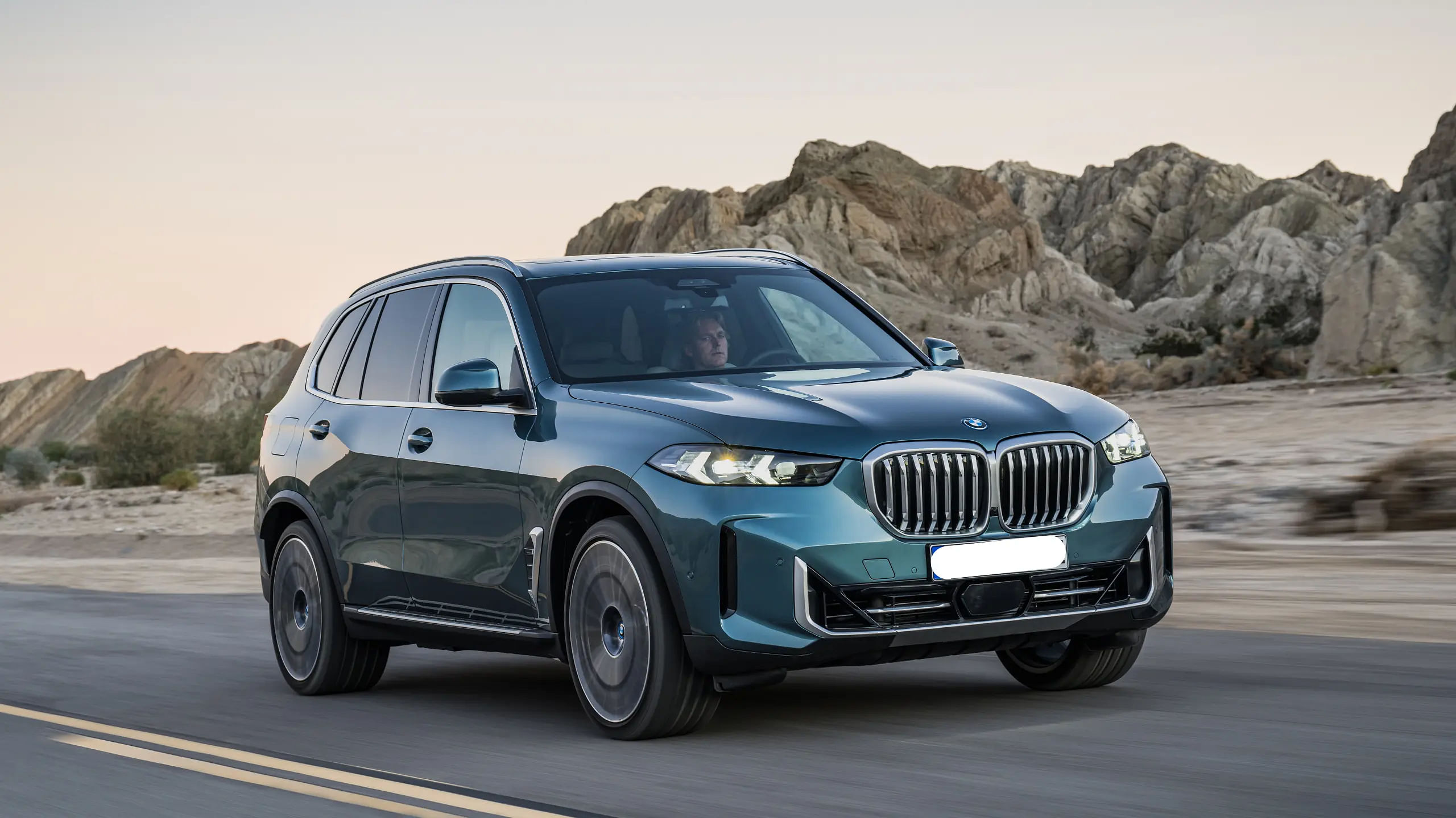 2024 BMW X5 driving down a road