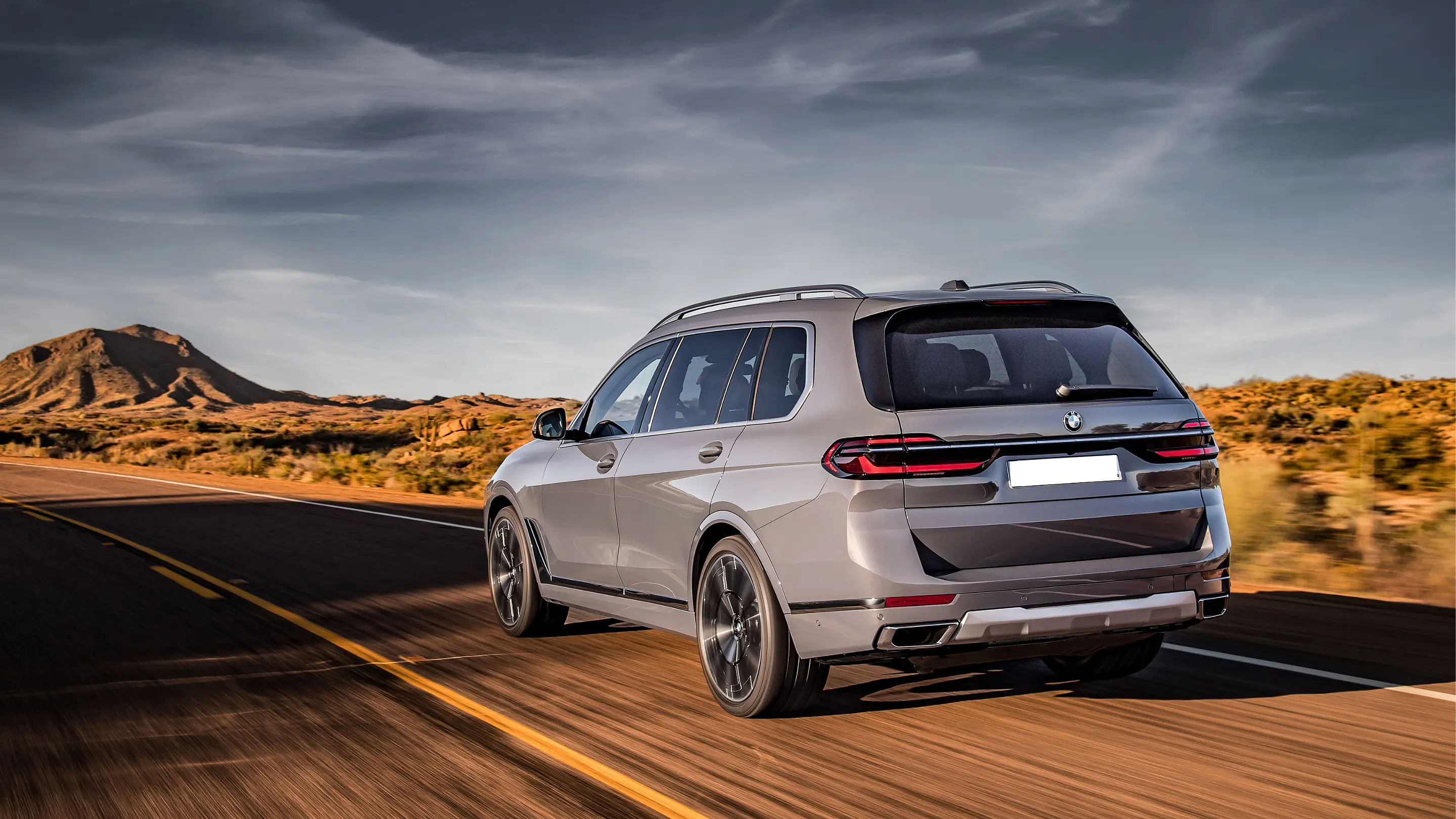 rear view 2024 BMW X7 driving down a road